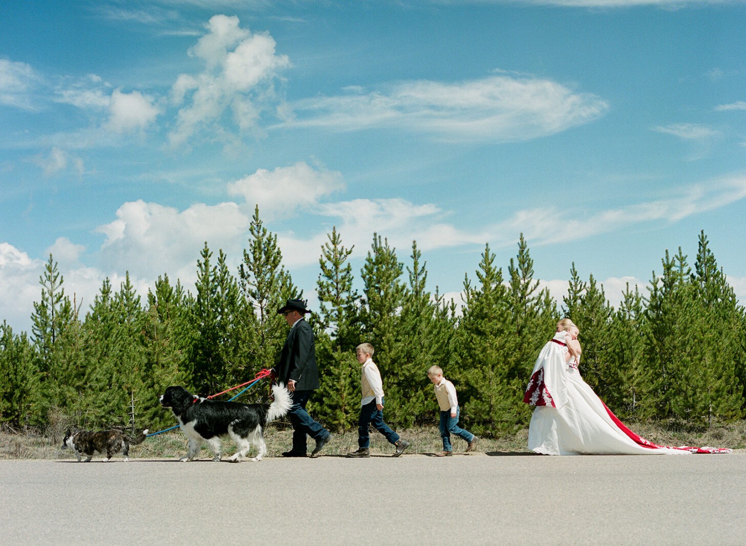 Anniversary photoshoot of family walking on a road in front of pine trees

