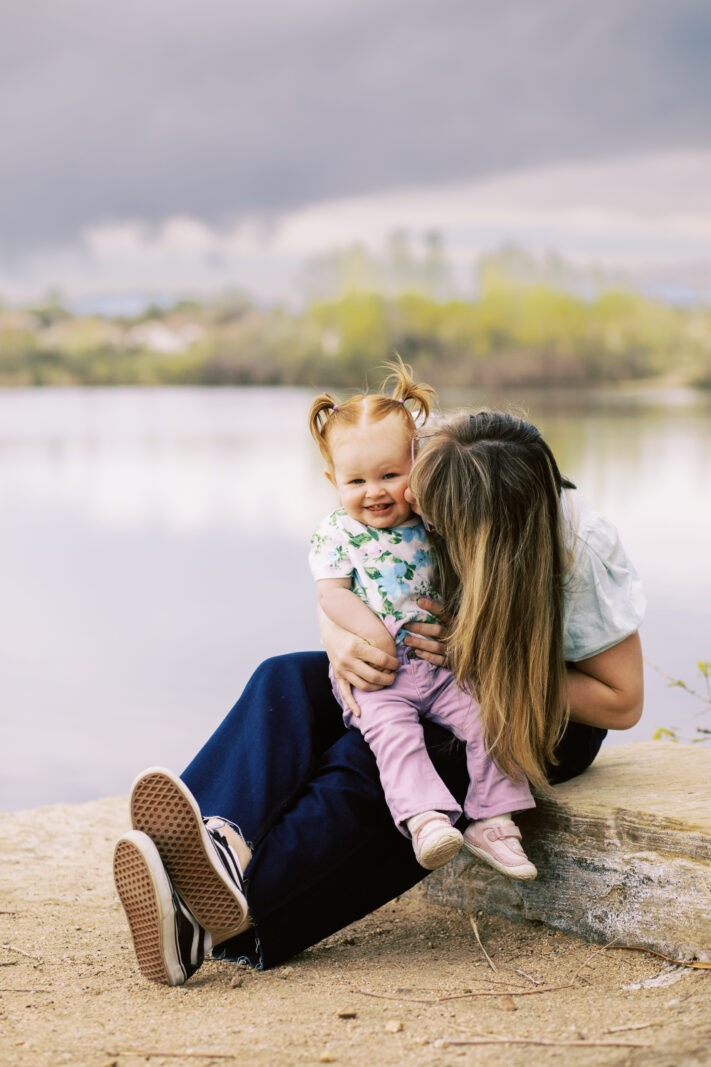 a mom kisses her toddler girl who has cute pigtails