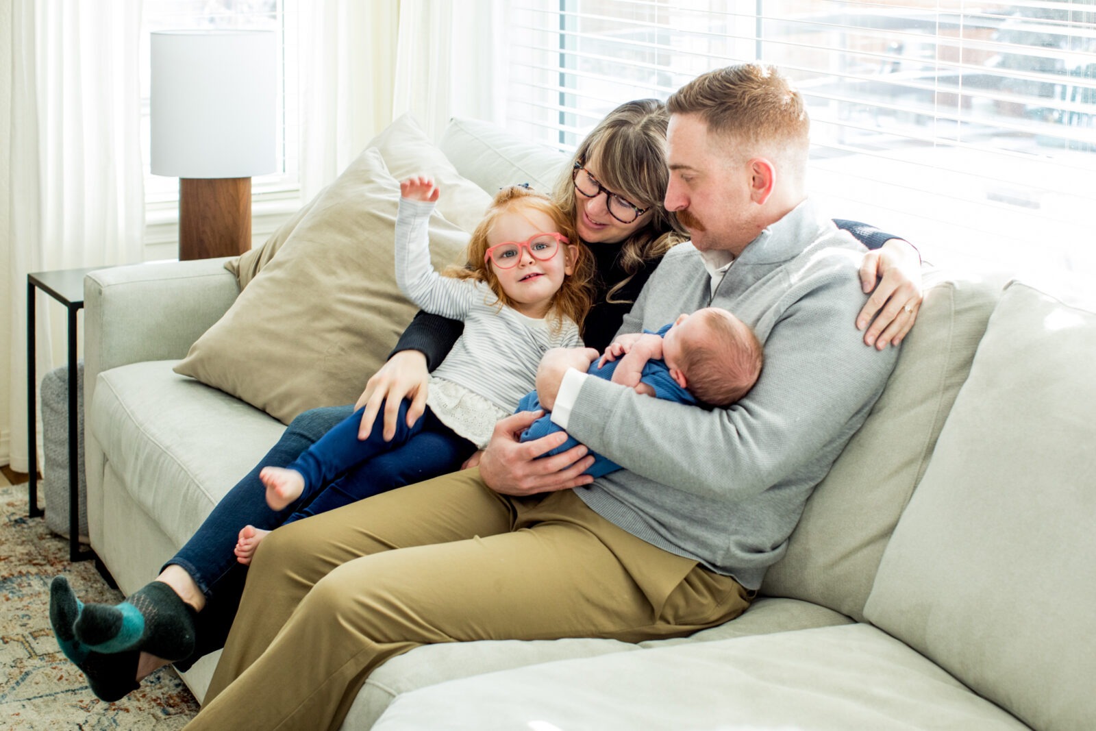 a family of four including a newborn and sister sit on a couch