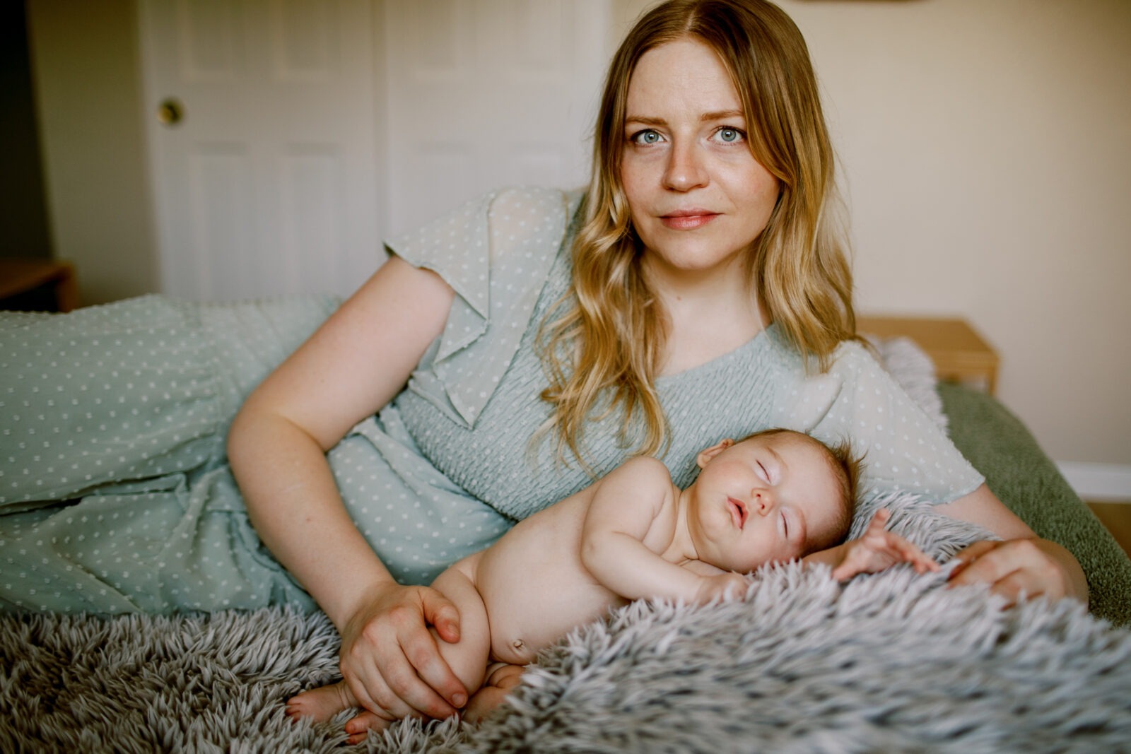 longmont colorado in-home baby photo session featuring a mom holding her baby girl on a bed