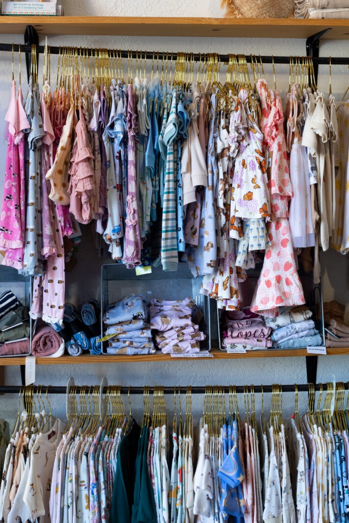 Rack of baby and toddler clothing at Adornables, a woman-owned children’s boutique in Old Town Longmont, Colorado, featuring organic fabrics, sustainable brands, and curated designs for families.