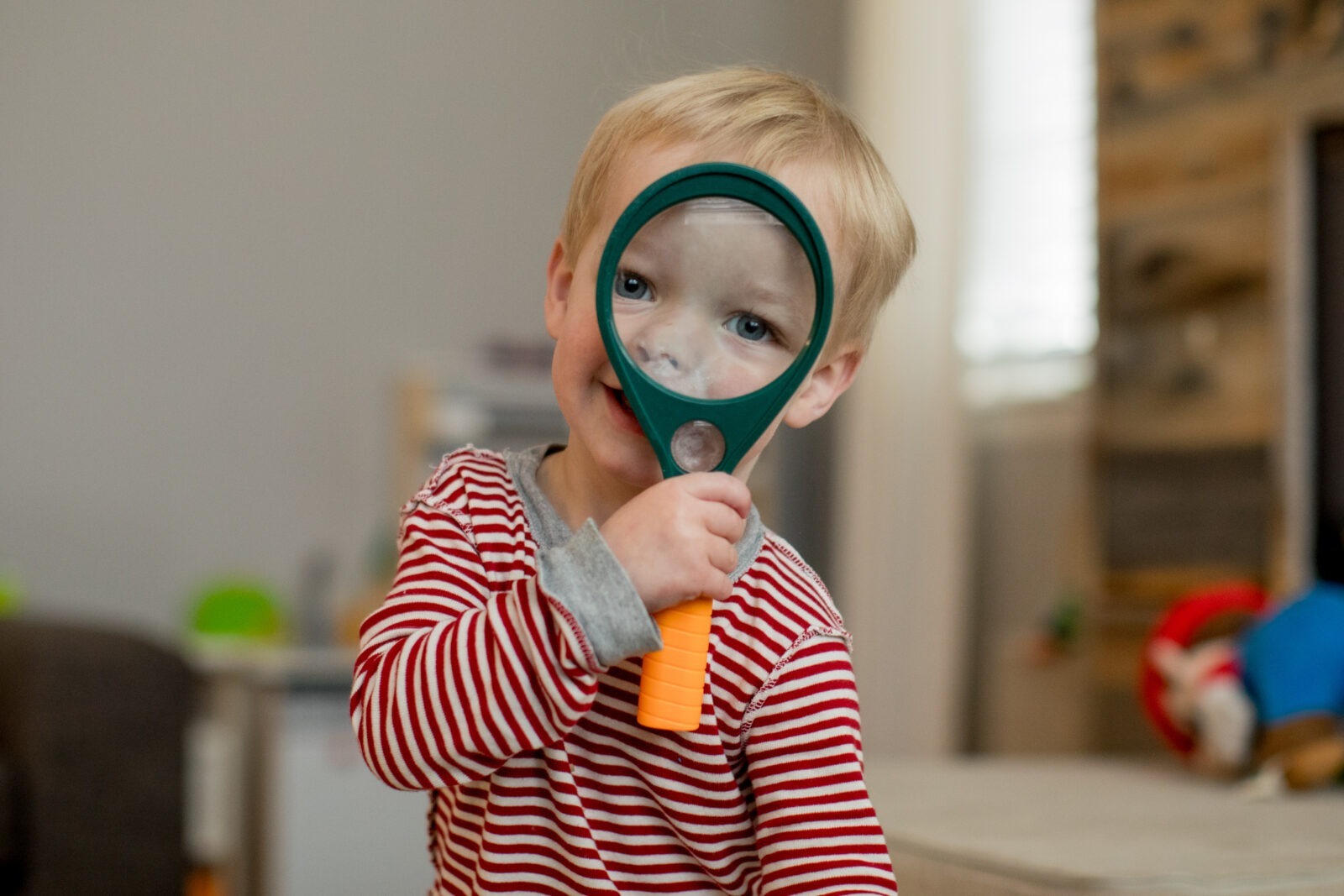 a boy looks through magnifying glass during a boulder in-home family session