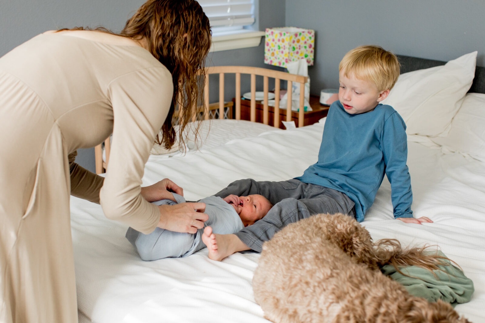 a mom adjusts the swaddle on her son during an in-home newborn photography session in erie, colorado