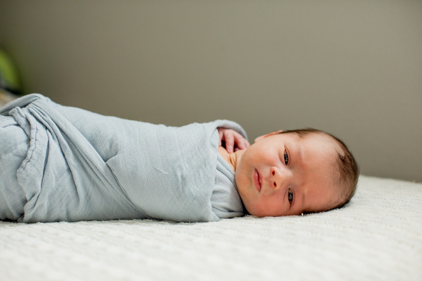 swaddled newborn baby boy during in-home photography session