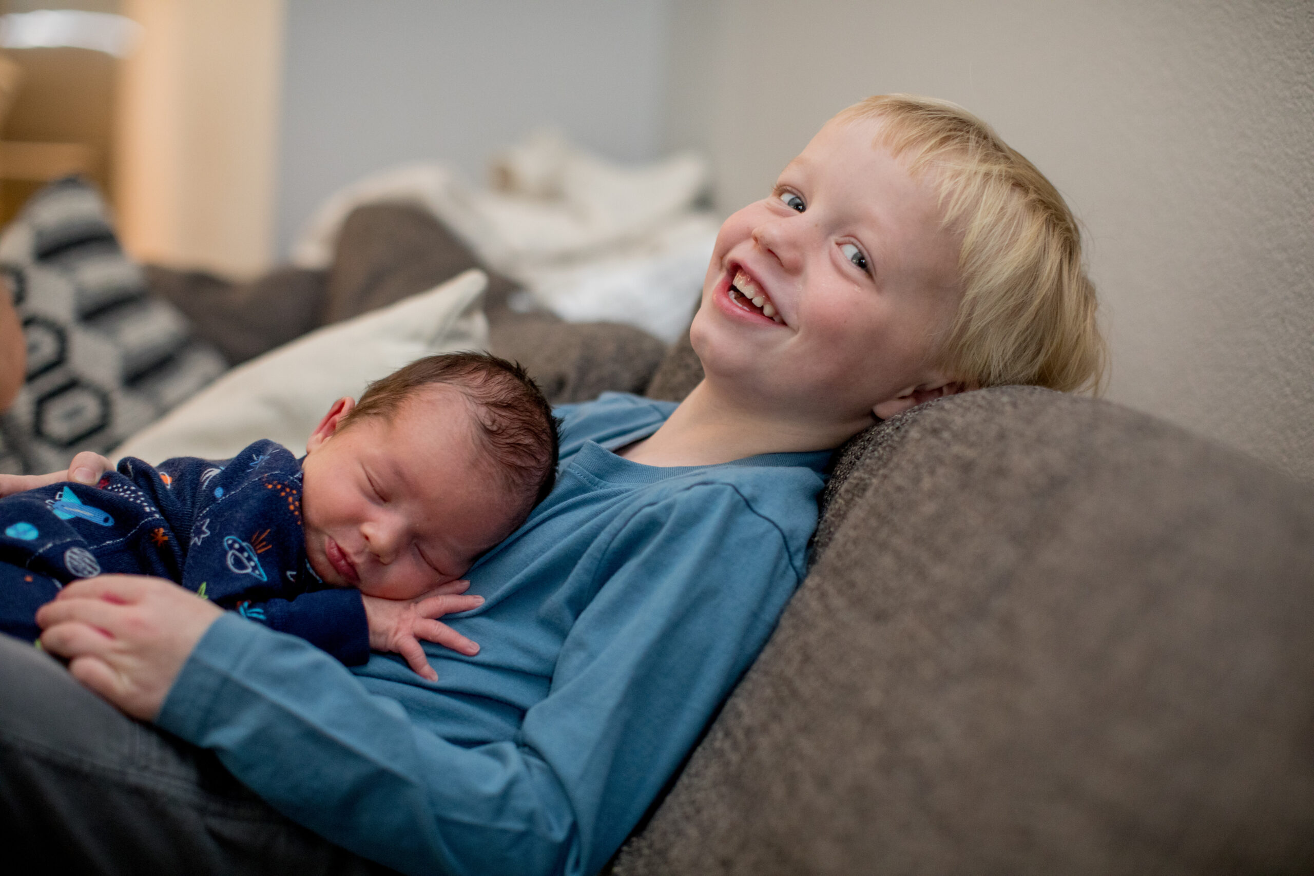 boy holds his newborn baby brother during an in-home newborn photography session