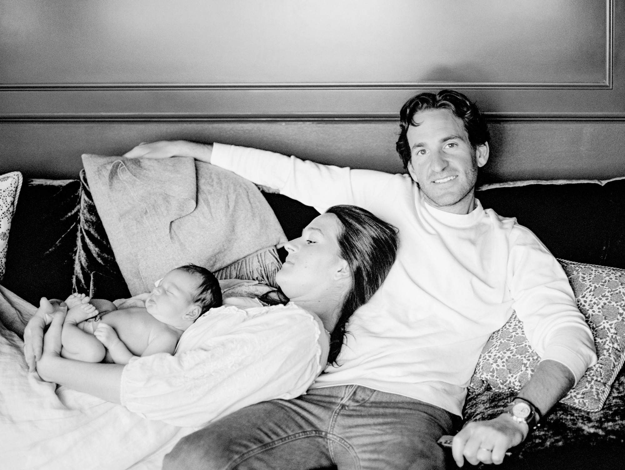 Parents relaxing on their living room couch holding their newborn during a candid in-home family photography session on Colorado’s Front Range
