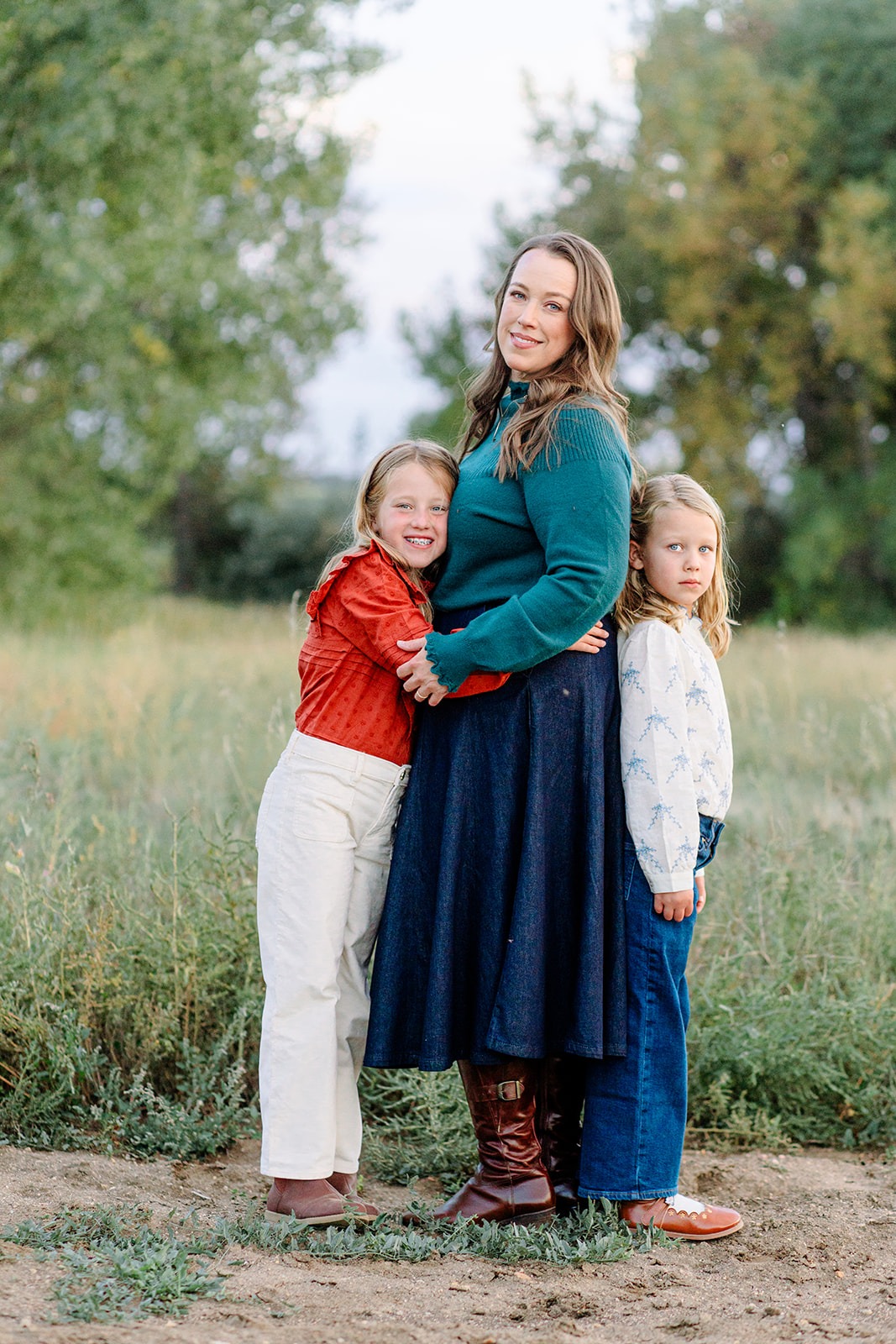 mom smiling with two daughters during outdoor spring mini session in Longmont Colorado